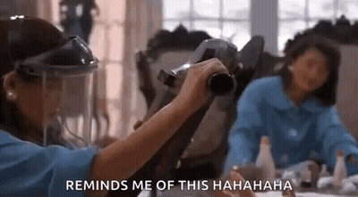 A Woman Wearing A Face Shield Is Holding A Camera In Front Of Another Woman . GIF