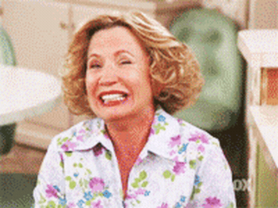 A Woman Wearing A Floral Shirt Is Laughing GIF