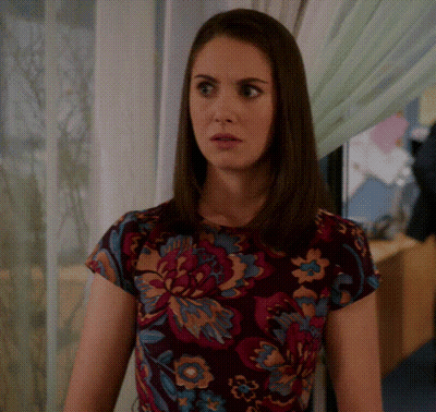 A Woman Wearing A Floral Shirt Is Looking At Something GIF