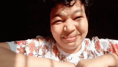 A Woman Wearing A Floral Shirt Is Smiling And Making A Face GIF