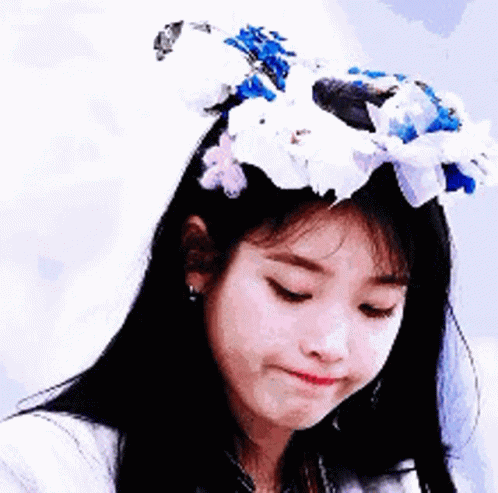 A Woman Wearing A Flower Crown On Her Head Is Making A Funny Face . GIF