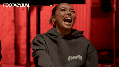 A Woman Wearing A Foota2yium Hoodie Laughs With Her Mouth Wide Open GIF