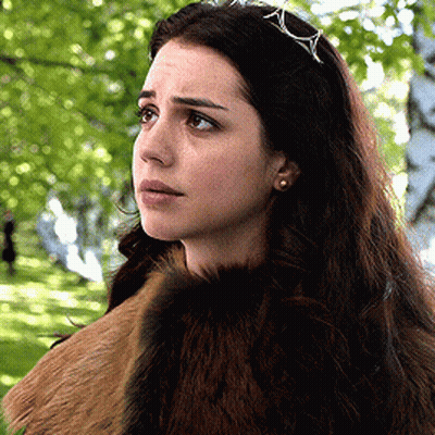 A Woman Wearing A Fur Coat And A Tiara Is Standing In A Park GIF