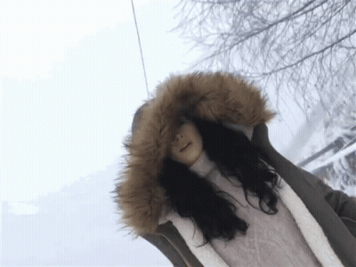 A Woman Wearing A Fur Hooded Jacket Is Standing In The Snow GIF