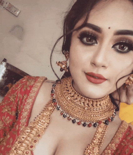 A Woman Wearing A Gold Necklace And Earrings Is Taking A Selfie GIF