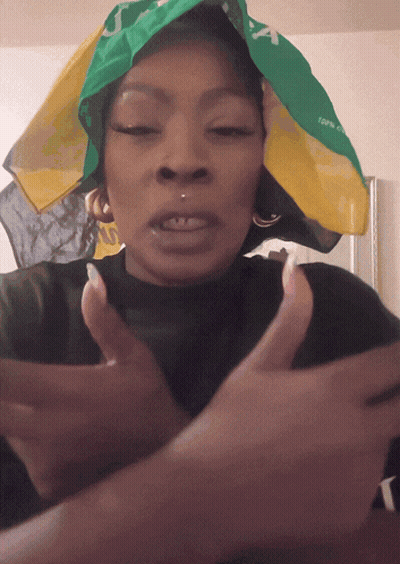 A Woman Wearing A Green And Yellow Bandana That Says Jamaica GIF