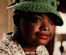 A Woman Wearing A Green Hat And A White Shirt Is Saying `` Eat My Shit '' . GIF