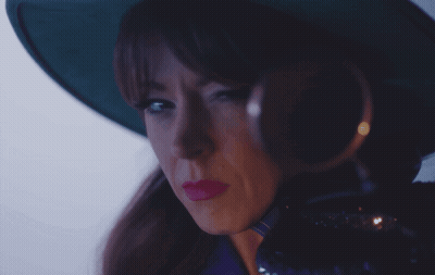 A Woman Wearing A Green Hat And Magnifying Glass GIF