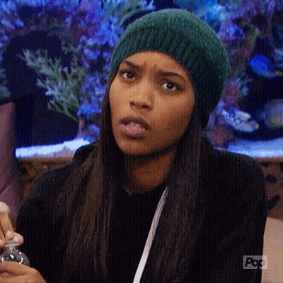 A Woman Wearing A Green Hat Is Making A Funny Face While Holding A Bottle . GIF