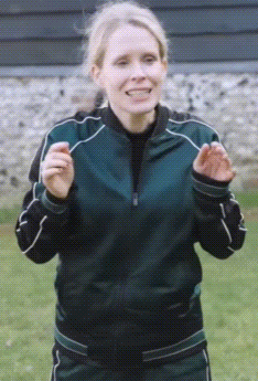 A Woman Wearing A Green Jacket And Black Pants Is Clapping GIF
