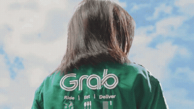 A Woman Wearing A Green Jacket That Says Grab On The Back GIF