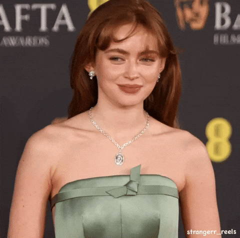 A Woman Wearing A Green Strapless Dress And A Necklace Is Standing In Front Of A Sign That Says Afta Awards GIF