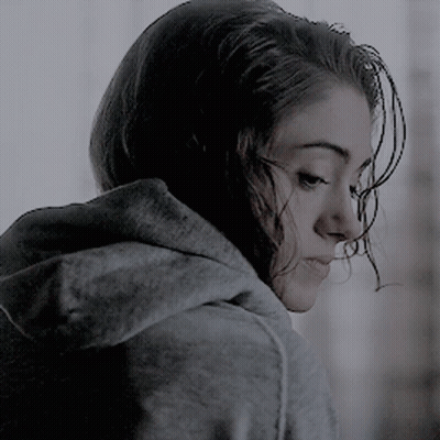 A Woman Wearing A Grey Hoodie Is Looking Down At Something GIF