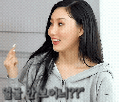 A Woman Wearing A Grey Hoodie With Korean Writing On The Sleeves GIF
