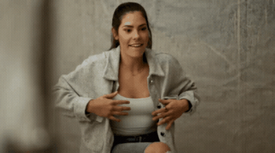 A Woman Wearing A Grey Jacket And White Tank Top GIF
