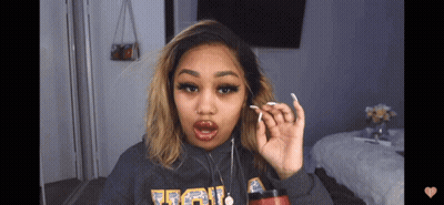 A Woman Wearing A Grey Sweatshirt With The Word Ucla On The Front GIF
