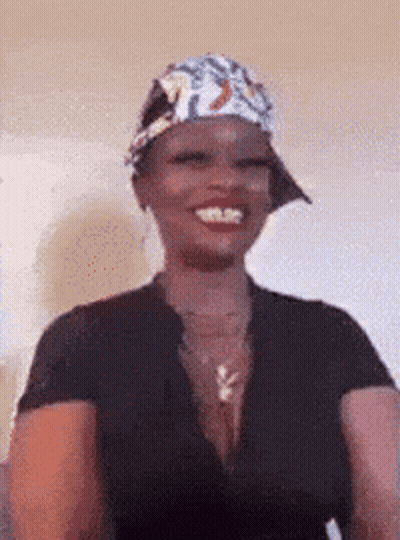 A Woman Wearing A Hat And A Black Shirt Smiles GIF