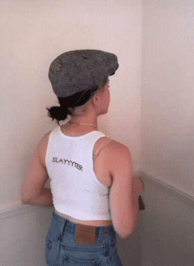 A Woman Wearing A Hat And A Tank Top That Says Slayer GIF