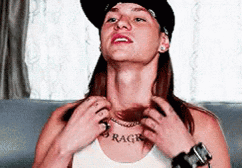 A Woman Wearing A Hat And A White Tank Top Has A Tattoo On Her Chest That Says Rage GIF