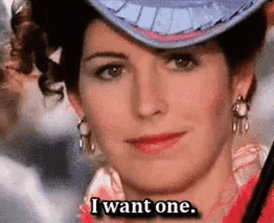 A Woman Wearing A Hat And Earrings Is Saying I Want One . GIF