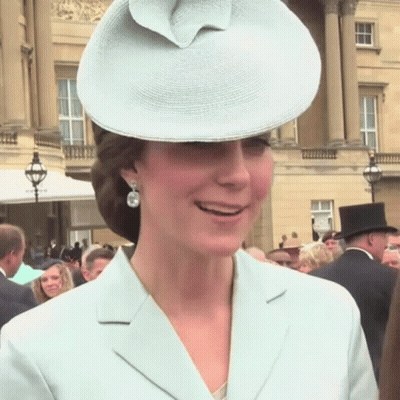 A Woman Wearing A Hat And Earrings Is Smiling GIF