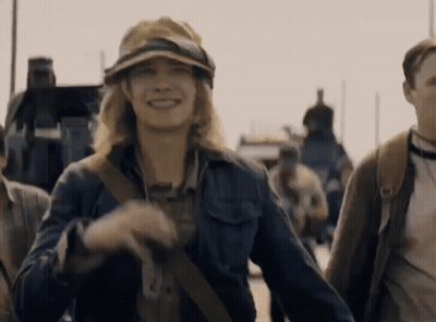 A Woman Wearing A Hat And Goggles Is Smiling In A Crowd Of People GIF