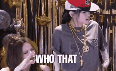 A Woman Wearing A Hat And Gold Chains Says Who That GIF