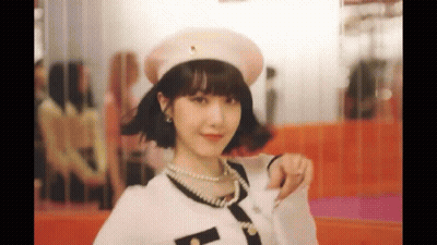 A Woman Wearing A Hat And Pearls Is Giving A Thumbs Up . GIF