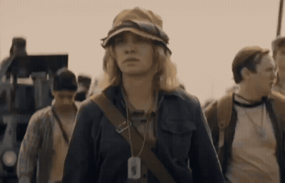 A Woman Wearing A Hat Has A Tag Around Her Neck That Says ' A ' On It GIF