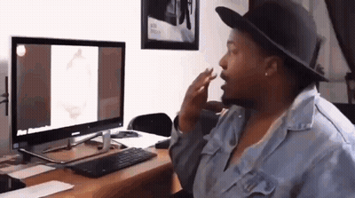 A Woman Wearing A Hat Is Sitting At A Desk In Front Of A Computer Monitor . GIF