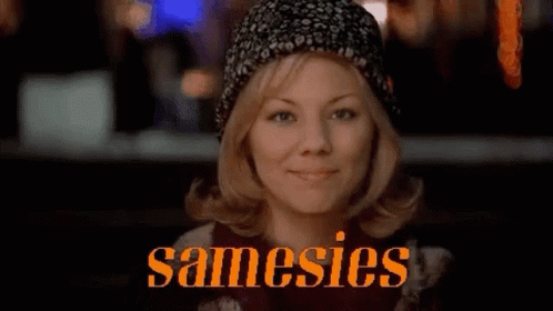 A Woman Wearing A Hat Is Smiling In Front Of A Sign That Says ' Samesies ' . GIF