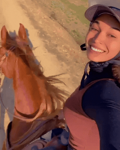 A Woman Wearing A Hat Is Smiling While Riding A Brown Horse GIF