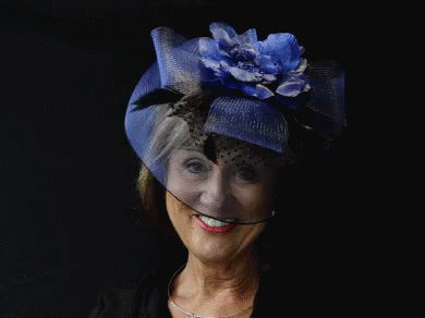 A Woman Wearing A Hat With A Blue Flower On It GIF