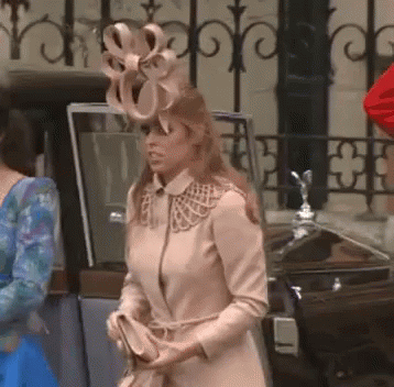 A Woman Wearing A Hat With A Bow On It Is Standing Next To A Car GIF