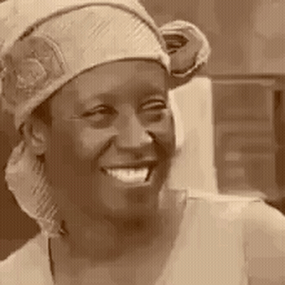 A Woman Wearing A Head Scarf And A Hat Is Smiling . GIF