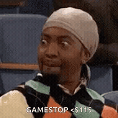 A Woman Wearing A Head Scarf And A Sweater Is Sitting In A Classroom . GIF