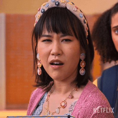 A Woman Wearing A Headband And Earrings Is Making A Funny Face GIF