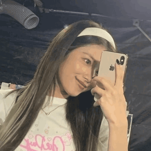 A Woman Wearing A Headband Is Taking A Selfie With Her Cell Phone . GIF