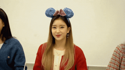 A Woman Wearing A Headband With Mickey Mouse Ears Says " Wait A Minute " GIF
