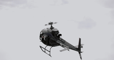 A Woman Wearing A Headset And Gloves Looks Out Of A Helicopter Window GIF