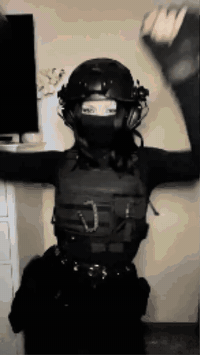 A Woman Wearing A Helmet And A Mask Is Standing In Front Of A Television . GIF