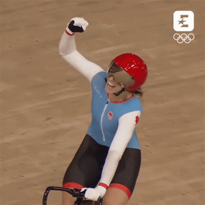 A Woman Wearing A Helmet And Goggles Is Riding A Bike And Raising Her Fist In The Air GIF