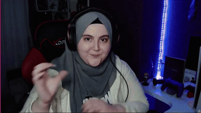 A Woman Wearing A Hijab And Headphones Is Sitting In A Chair GIF