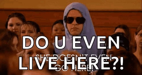 A Woman Wearing A Hijab And Sunglasses Stands In Front Of A Crowd And Says Do U Even Live Here GIF
