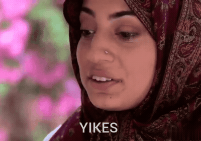A Woman Wearing A Hijab Says " Yikes " In Front Of Her Face GIF