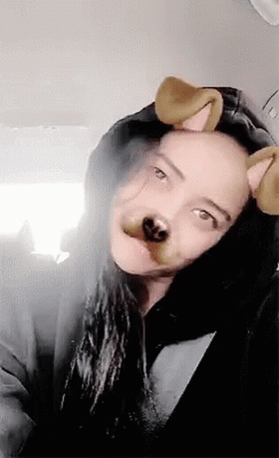A Woman Wearing A Hooded Jacket And Dog Ears Looks At The Camera . GIF