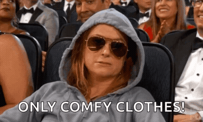 A Woman Wearing A Hoodie And Sunglasses Is Sitting In A Theater . GIF