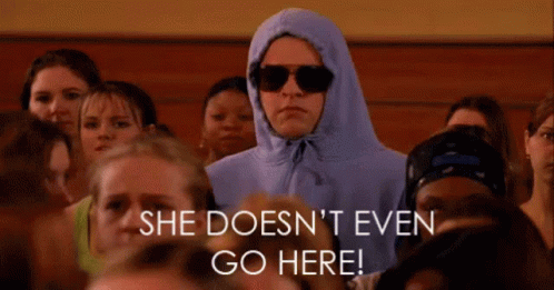 A Woman Wearing A Hoodie And Sunglasses Stands In A Crowd Of People With The Words She Does N't Even Go Here GIF