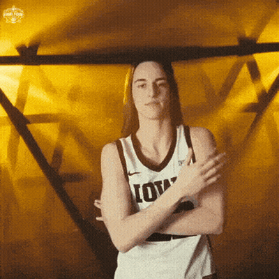 A Woman Wearing A Iowa Jersey Is Standing With Her Arms Crossed GIF