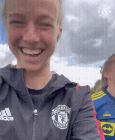 A Woman Wearing A Jacket That Says Manchester United On It GIF